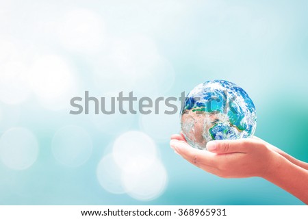 Blue planet in human hands on blurred beautiful blue sky background. Ecology, World Environment Day, Investment, CSR, Health Care, Healthcare concept. Elements of this image furnished by NASA.