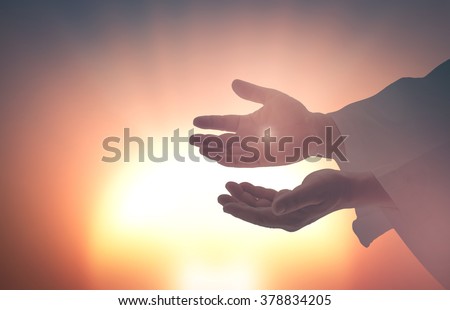 Silhouette the hands of Jesus Christ opening palm up and showing scars on blurred spiritual light background. Resurrection Humble Redeemer Eucharist Blessed Christian Give Trust Nail Religion concept.