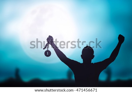 Human hand raised, holding gold medal against sky. Arm Win Goal First Moon Photo Prize Best Match Olympic Hero Metal Cloud Aim Green Blue Day Many Pride Crowd Banner Champ Badge Contest Place Night