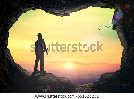 Faith concept: Silhouette of human standing to worship God in mountain sunset background.