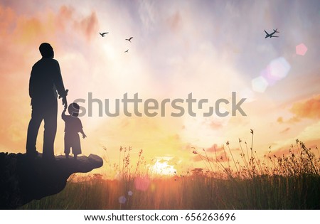 Father\'s Day concept: Silhouette child\'s hand holding father\'s finger on mountain sunset background.