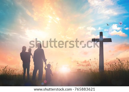 Family worship concept: Silhouette father mother and two son looking for the cross on autumn sunrise background.