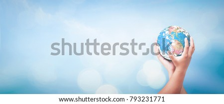 World environment day concept: Two human hands holding earth globe over blurred blue sky background. Elements of this image furnished by NASA.