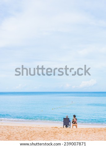 senior couple of old man and woman sitting on the beach looking on the horizon .