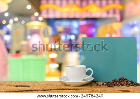 White cup of coffee and green chalkboard menu on wooden bar with Coffee shop blur background with bokeh image .