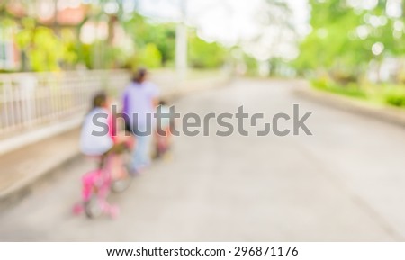 blur image of people riding bike in public park on day time for background usage.