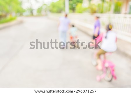 blur image of people riding bike in public park on day time for background usage.