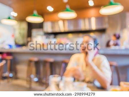 blur image of woman use mobile phone in coffee shop for background usage.