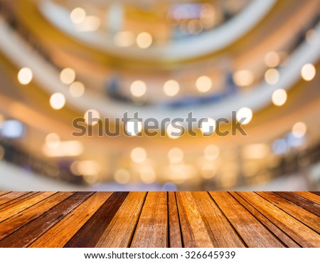 blurred image of wood table and trade show in shopping mall for background usage .