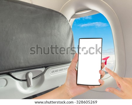 male hand is holding a modern touch screen phone and image of seat on airplane.