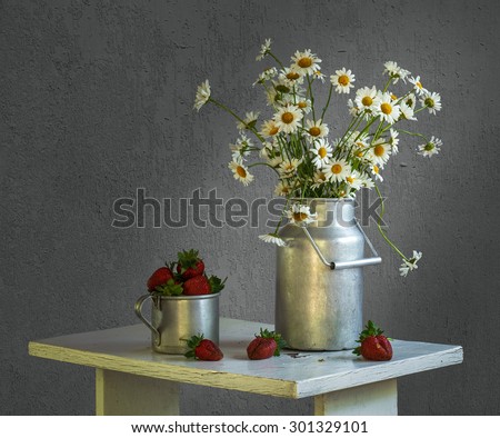 Bouquet of daisies in aluminum cans and strawberries in a bowl