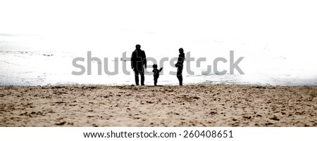 Happy family playing with her child on the beach. Family silhouettes on the beach in The morning. Copy space. . Extreme Wide Shot.
