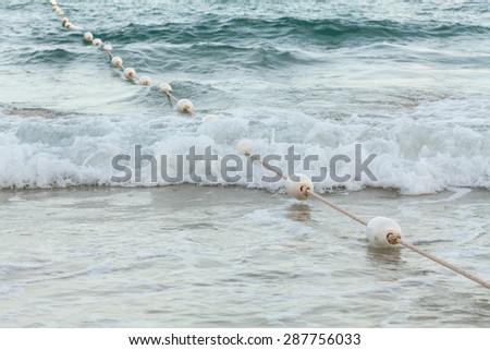 White foam buoys strung with nylon rope barrier, a boundary in the sea.