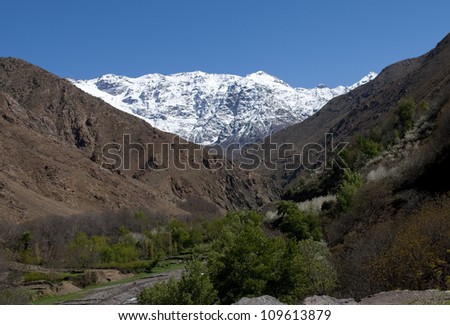 March 2012. In the Atlas Mountains. Morocco with snow on the tops seen through a green arable valley with brown hill sides