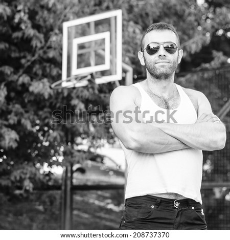 Athletic sexy strong man  in a white sleeveless shirt with sunglasses