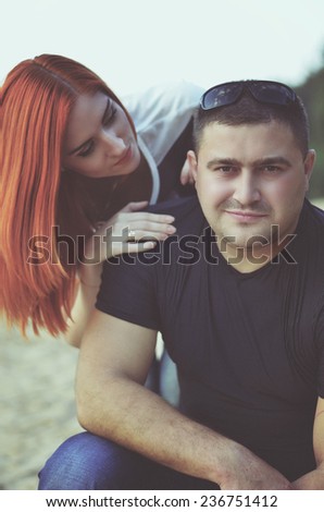 Portrait of a loving young woman embracing man from behind  in the park