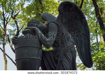 Angel statue with the funeral urn in cemetery