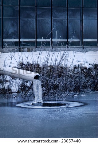 Frozen industry: frozen sewage pipe next to a factory