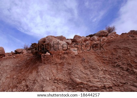 A view of brown soil, rocks and roots under beautiful sky