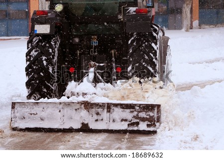 Cleaning street from snow by tractor on a street