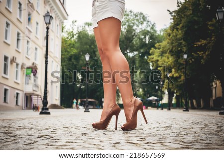 woman tan legs in high heel brown shoes outdoor shot summer day