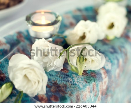 Delicate white roses with white candle on the table.
