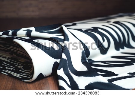 Fashionable white textile roll with black letters on wooden background