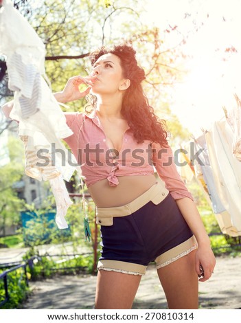 Pin up, vintage style photo of woman doing laundry and smoking