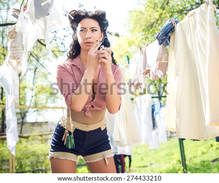 Pin up, vintage style photo of woman doing laundry and smoking
