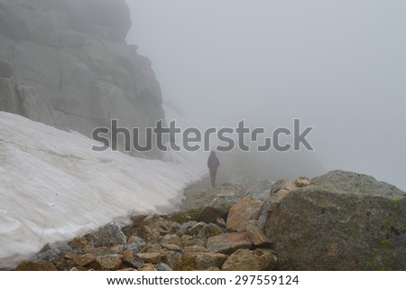 Young woman on a rocky mountain road in a fog