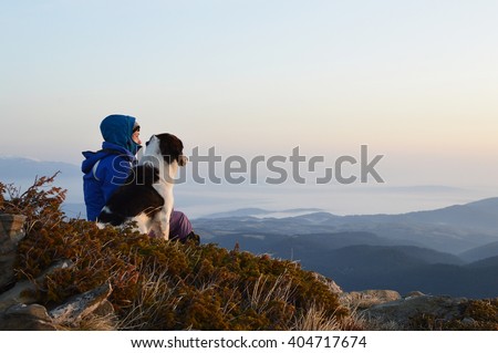 Young woman with dog watching sunrise high in the mountain, Rila Mountains, Bulgaria
