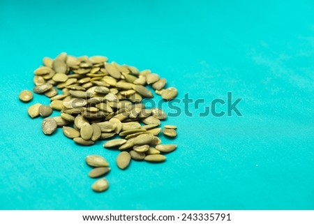 Pile of pumpkin seeds on turquoise background