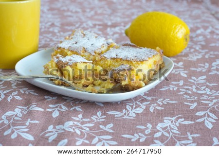 Fresh lemon cake, yellow cup and lemon fruit on patterned fabric