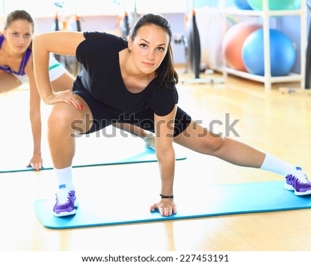 Young woman doing stretching exercises on the floor at the gym