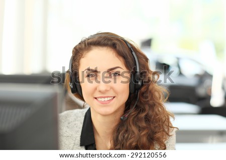 Smiling girl - operator in headphones, sitting at the computer. Customer service agent