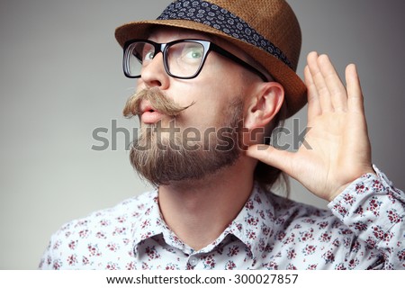 Portrait of young hipster cupping hand behind ear - can\'t hear you concept