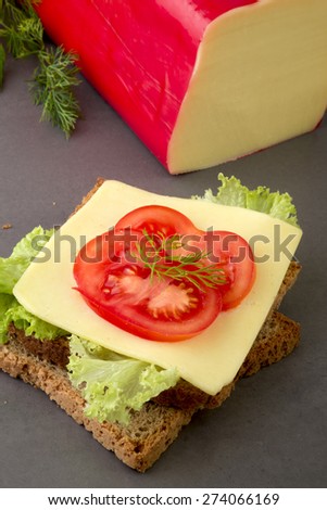 Slice of gouda & edam cheese on wholegrain toast bread garnished with tomato slices.