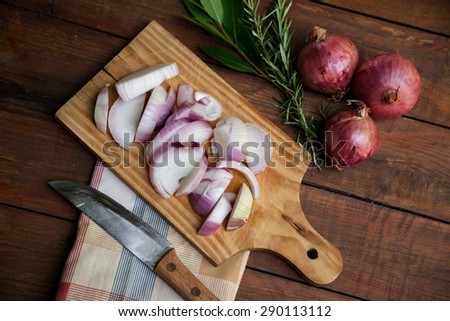 Chopped onions and knife on wooden chopping board, laurel leaves , kitchen cloth on a nice rustic background