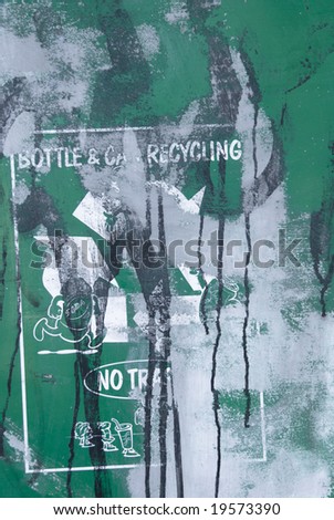 Defaced recycling sign seen in a run-down park