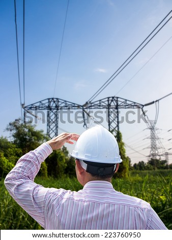 Young engineer looking work in front of transmission towers