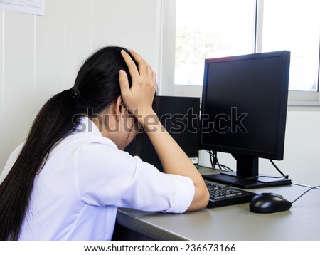 Tired or depressed Business woman sitting at he desk behind he laptop with he hands covering he eyes