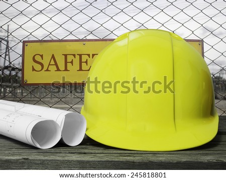 yellow safety hat on wood table over blurred construction site