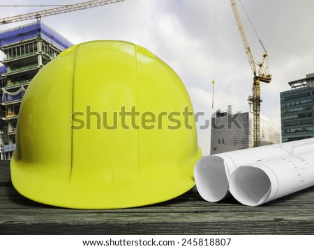 yellow safety hat on wood table over blurred construction site