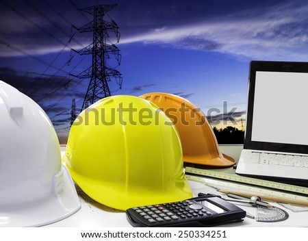 safety helmet and architect blueprints on table over building construction background