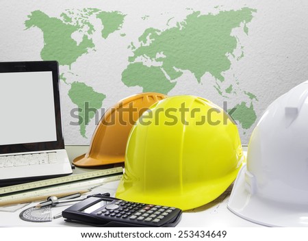 safety helmet and architect blueprints on table over world map background