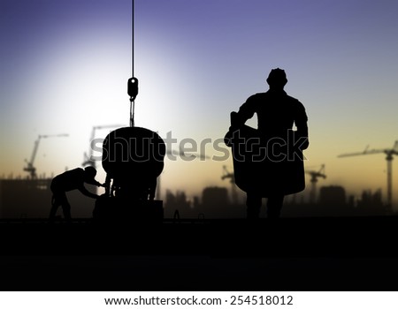 silhouette engineer looking at blueprints in a building site over Blurred construction worker