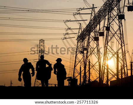 Silhouette man of engineer looking at blueprints in a building site over Blurred substation