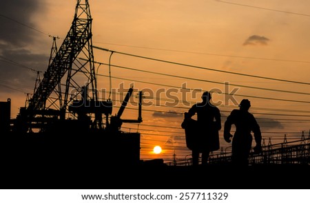 Silhouette of engineer looking at blueprints in a building site over Blurred substation