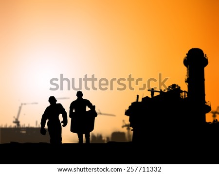 Silhouette man of engineer looking at blueprints in a building site over Blurred Power Plant