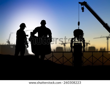 silhouette engineer looking at blueprints in a building site over Blurred construction worker on construction site